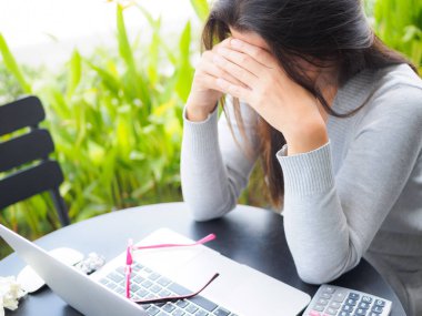 Genç Asyalı kadın baş ağrısı bir kafeterya bahçesinde bulunan onu laptop, stresli iş için otururken.