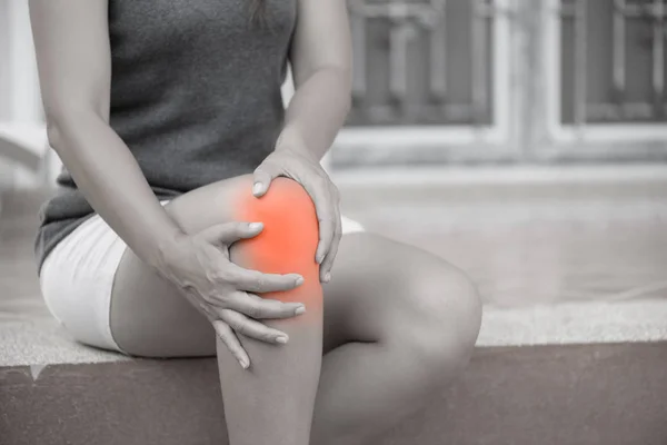 Closeup jonge vrouw gevoel pijn in haar knie thuis. — Stockfoto