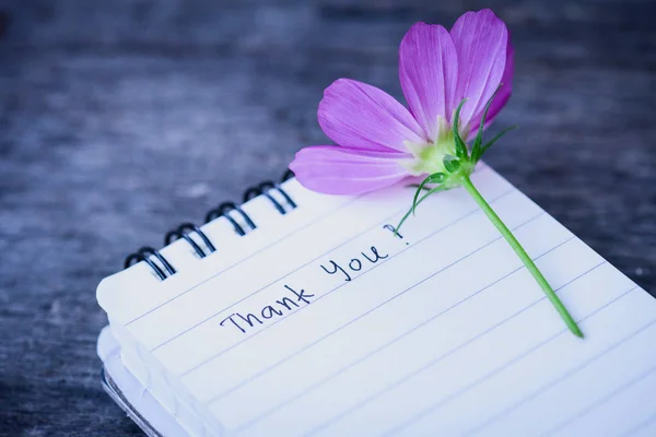 Dankeschön-Text auf weißem Notizbuch mit romantischer weißer Blume auf hölzernem Hintergrund. — Stockfoto