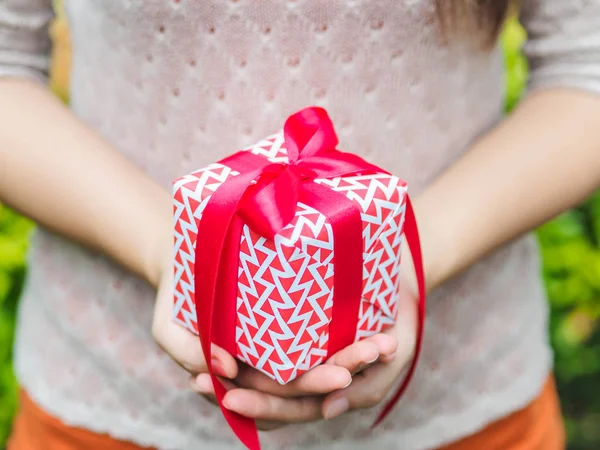 Mano femminile in possesso di una confezione regalo con nastro rosso . — Foto Stock