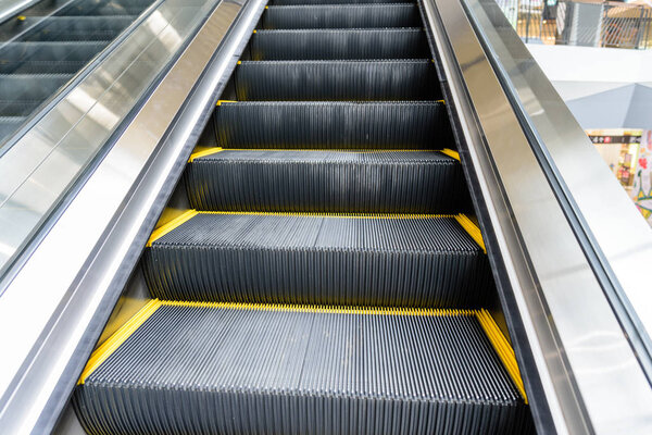 Close up escalator with yellow line in shopping mall.