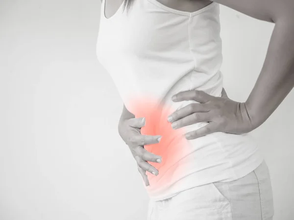 Vrouw met een buikpijn of menstruatiepijn met witte achtergrond. Gezondheidszorg en medische concept. — Stockfoto