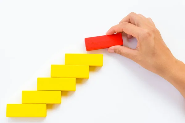 Concept of building success foundation. Women hand put red wooden block on yellow wooden blocks in the shape of a staircase — Stock Photo, Image