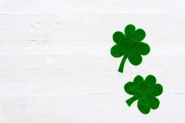 Feliz día de San Patricio mensaje sobre el trébol de papel verde y fondo de madera blanca — Foto de Stock