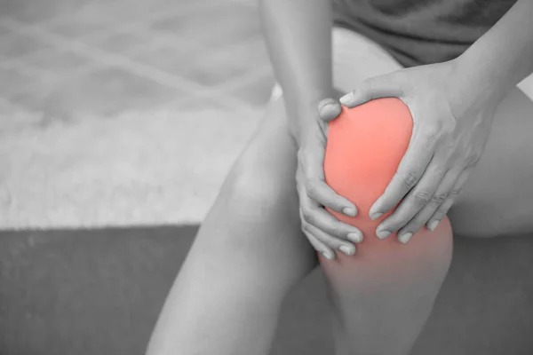 Närbild ung kvinna känner smärta i hennes knä hemma. — Stockfoto