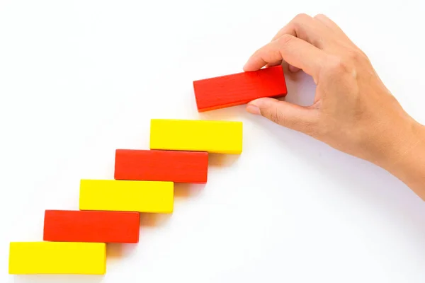 Concept of building success foundation. Women hand put red wooden block on yellow wooden blocks in the shape of a staircase — Stock Photo, Image