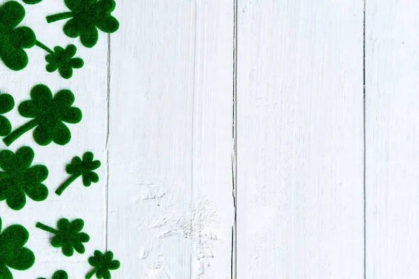Happy st patricks day message und viel grünes Papier Kleeblatt auf weißem Holzgrund — Stockfoto