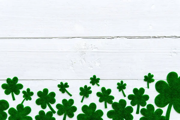 Happy st patricks day message und viel grünes Papier Kleeblatt auf weißem Holzgrund — Stockfoto