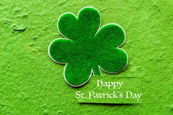 Happy St Patricks Day message on green paper clover and bright green Mulberry paper background