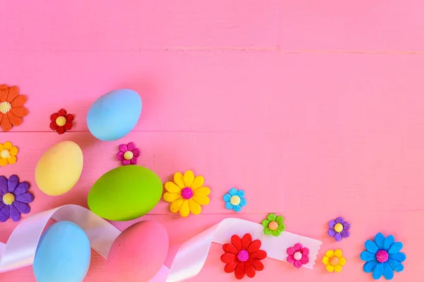 Easter eggs with colorful paper flowers on bright pink wooden background. — Stock Photo, Image