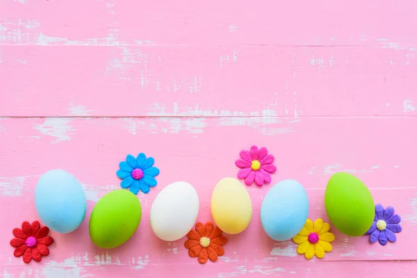 Fila de ovos de Páscoa com flores de papel coloridas em fundo de madeira rosa e branco brilhante . — Fotografia de Stock