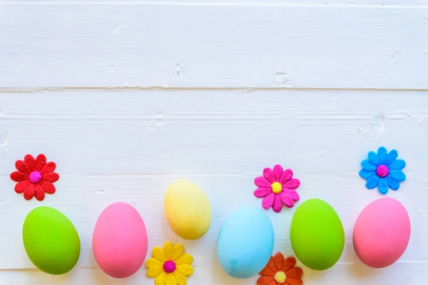 Row Easter eggs with colorful paper flowers on bright pink and white wooden background. — Stock Photo, Image