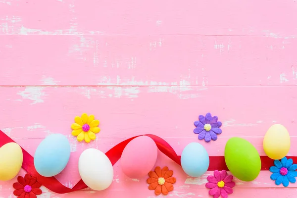 Row Easter eggs with colorful paper flowers on bright pink and white wooden background. — Stock Photo, Image