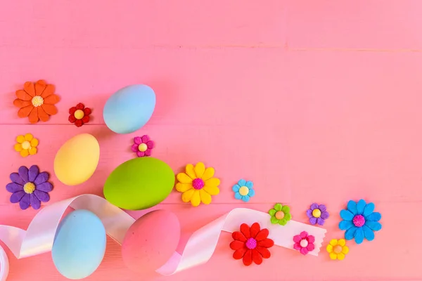 Easter eggs with colorful paper flowers on bright pink wooden background. — Stock Photo, Image