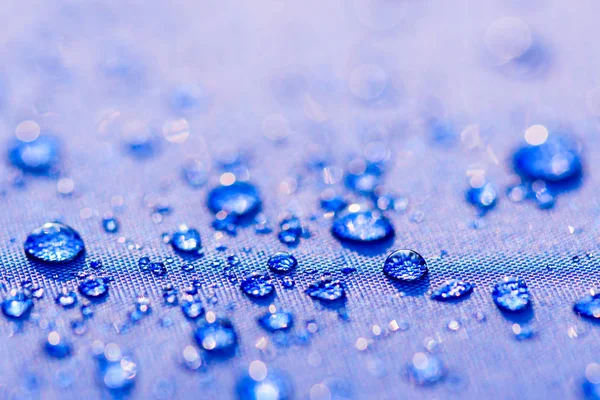 Fermer Modèle gouttes d'eau sur un fond en tissu imperméable bleu. Concept de Journée mondiale de l'eau . — Photo