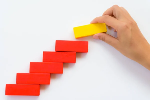 Concept of building success foundation. Women hand put yellow wooden block on red wooden blocks in the shape of a staircase — Stock Photo, Image