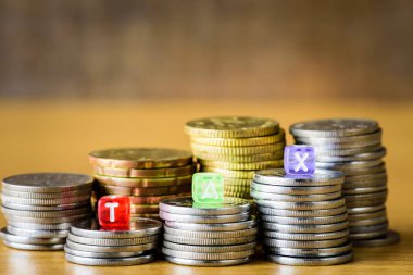 Vergi kavramı ile bir altın sikkeleri yığılmış blokta alfabesi.