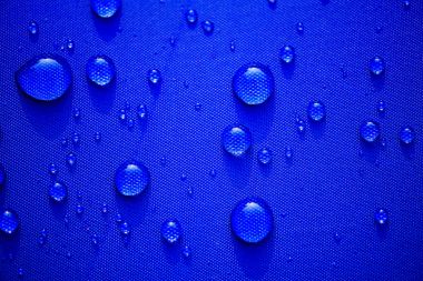 Su yakından desen mavi su geçirmez kumaş arka plan üzerinde bırakır. Dünya Su günü kavramı.