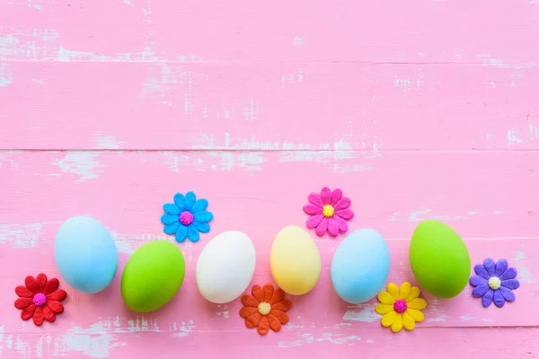 Fila huevos de Pascua con flores de papel de colores sobre fondo de madera rosa brillante y blanco . — Foto de Stock