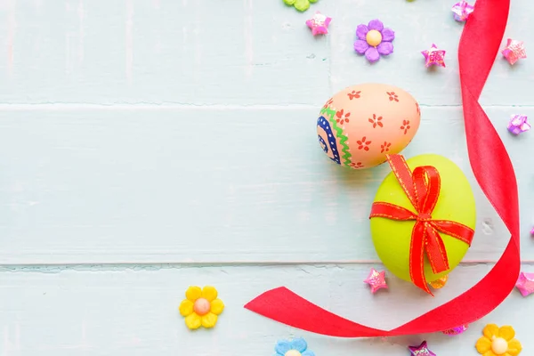 Happy easter! Colorful of Easter eggs with red ribbon and colorful of paper flower and paper star on pastel color bright green and white wooden background. — Stock Photo, Image