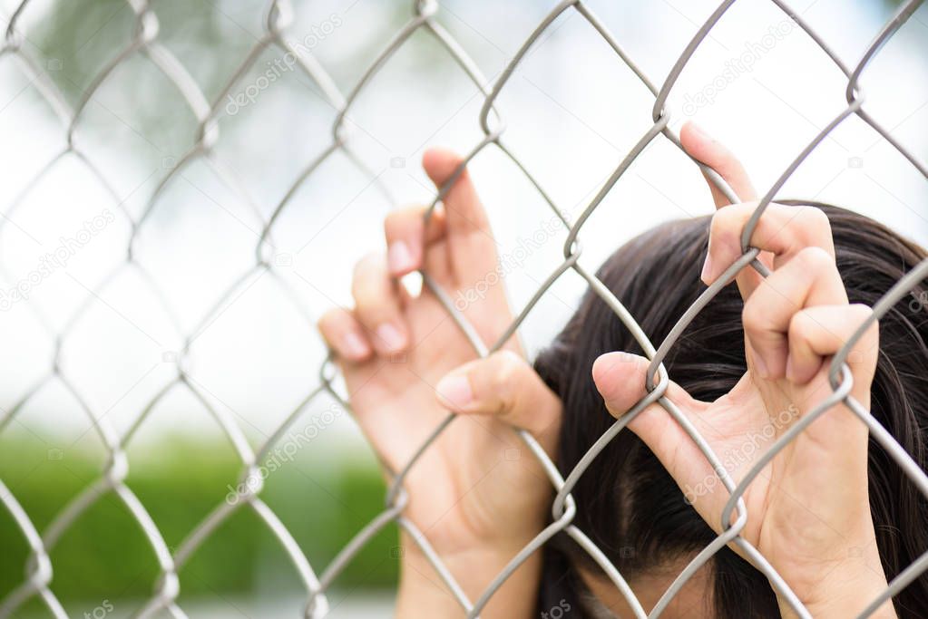 Woman hand holding on chain link fence for freedom