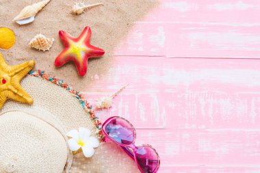 Plaj aksesuarları, güneş gözlüğü de dahil olmak üzere deniz yıldızı, şapka plaj ve kabuk üzerinde parlak pembe pastel ahşap arka plan yaz tatil ve tatil konsepti için.