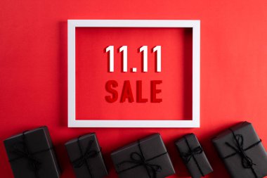 Çin 'de online alışveriş, 11.11 bekarlar günü konsepti. Beyaz resim çerçevesinin üst görünümü, kırmızı zemin üzerinde siyah hediye kutusu ve metin 11: 11 single indirimi için kopya alanı var..
