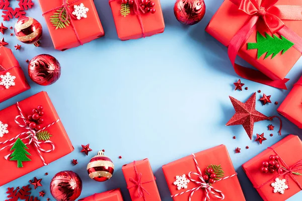 Χριστουγεννιάτικο φόντο. Κορυφή άποψη των Χριστουγέννων κόκκινο κουτί δώρου με ζαχαροκάλαμο καραμέλα, νιφάδες χιονιού, κόκκινα μούρα και καμπάνα σε μπλε παστέλ φόντο. — Φωτογραφία Αρχείου
