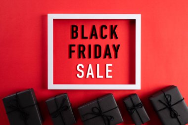 Siyah Cuma İndirimi 'nin en iyi görüntüsü beyaz çerçeveli, siyah hediye kutusu ve kırmızı arka planda Noel topu ve böğürtlenli. Alışveriş konsepti ve Kara Cuma kompozisyonu.