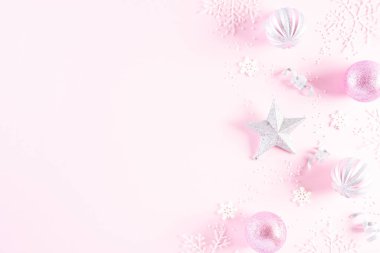 Noel konsepti. Açık pembe pastel arka planda kar taneleri olan Noel balosunun en üst görüntüsü.