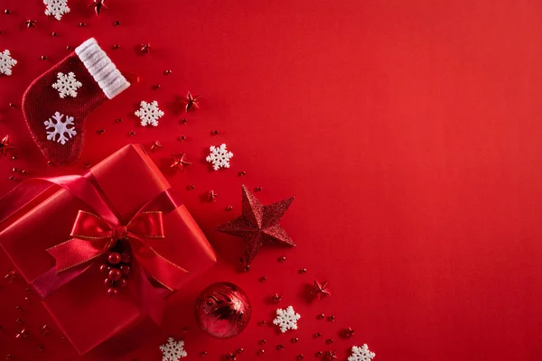 Χριστουγεννιάτικο φόντο. Κορυφή άποψη των Χριστουγέννων κόκκινο κουτί δώρου με κάλτσες διακόσμηση, έλατο κλαδιά, αστέρι, κόκκινα μούρα και νιφάδες χιονιού σε κόκκινο φόντο. — Φωτογραφία Αρχείου