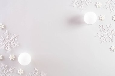 Noel konsepti. Açık gri pastel arka planda kar taneleri olan Noel balosunun en üst görüntüsü.
