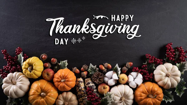 Sonbahar akçaağaç yaprakları, balkabağı ve kırmızı böğürtlenli siyah ahşap arka plan. Şükran Günü konsepti.