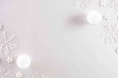Noel konsepti. Açık gri pastel arka planda kar taneleri olan Noel balosunun en üst görüntüsü.