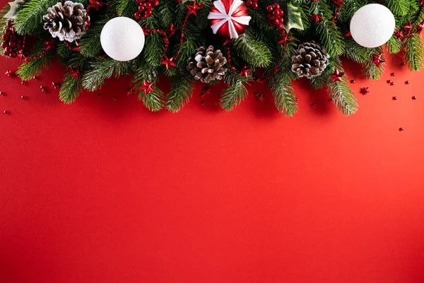 Karácsonyi háttérkoncepció. Top view karácsonyi ajándék doboz piros golyók lucfenyő ágak, fenyőtoboz, piros bogyó csillag és harang piros háttér. — Stock Fotó