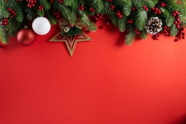 Noel konsepti. Noel hediye kutusunun üst görüntüsü ladin dalları, çam kozalakları, kırmızı böğürtlen yıldızı ve kırmızı zili olan kırmızı toplar..
