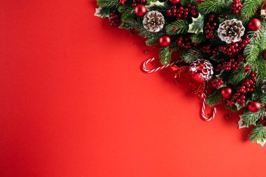 Noel konsepti. Noel hediye kutusunun üst görüntüsü ladin dalları, çam kozalakları, kırmızı böğürtlen yıldızı ve kırmızı zili olan kırmızı toplar..