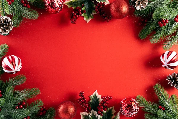 Noel concept de fond. Vue du dessus du coffret cadeau de Noël boules rouges avec branches d'épinette, cônes de pin, étoile de baies rouges et cloche sur fond rouge. — Photo