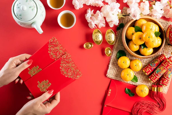 Китайские новогодние украшения. Женщина держит пак или красный пакет, оранжевые и золотые слитки на красном фоне. Китайские иероглифы FU означает удачу, богатство, денежный поток . — стоковое фото
