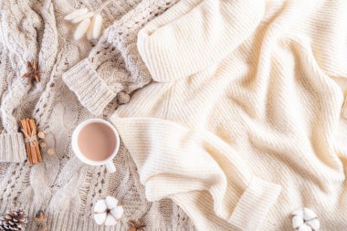 Sonbahar veya kış kompozisyonu. Kahve fincanı, tarçın çubukları, anason yıldızları krema rengi örülmüş bej süveter battaniye arka planı. Düz görünüm kopyalama alanı.
