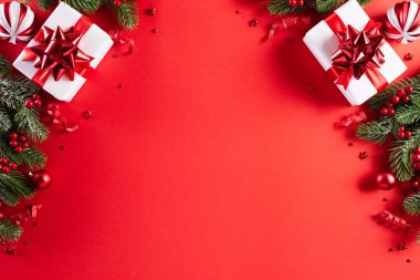 Noel konsepti. Noel hediye kutusunun üst görüntüsü ladin dalları, çam kozalakları, kırmızı böğürtlen yıldızı ve kırmızı zili olan kırmızı toplar..