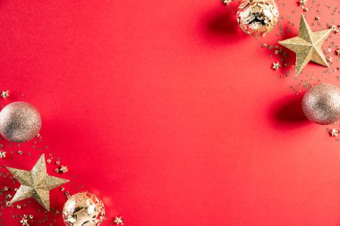 Noel konsepti. Noel altın toplarının ve açık kırmızı pastel arka planda kar taneleri olan yıldızların en üst görüntüsü.