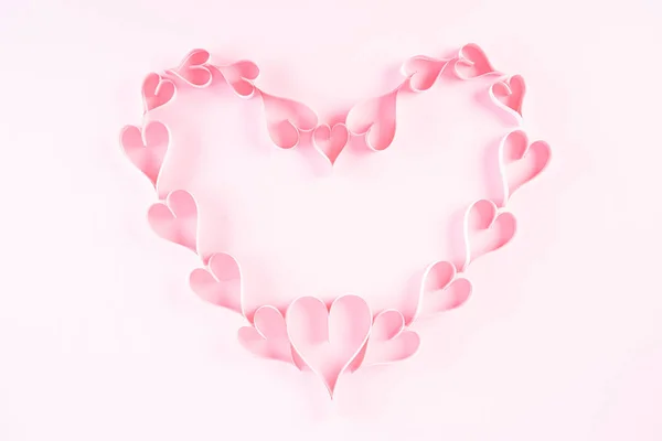Açık pembe renkli kağıt arka planda kalp şeklinde küçük pembe kağıt kalpler. Aşk ve Sevgililer Günü konsepti. — Stok fotoğraf