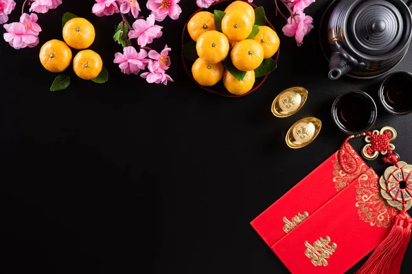 Çin Yeni Yıl Festivali dekorasyonları siyah arka planda kırmızı paket, turuncu ve altın külçeler veya altın topak. Çin karakterleri Fu servet, servet, para akışı anlamına gelir.. — Stok fotoğraf