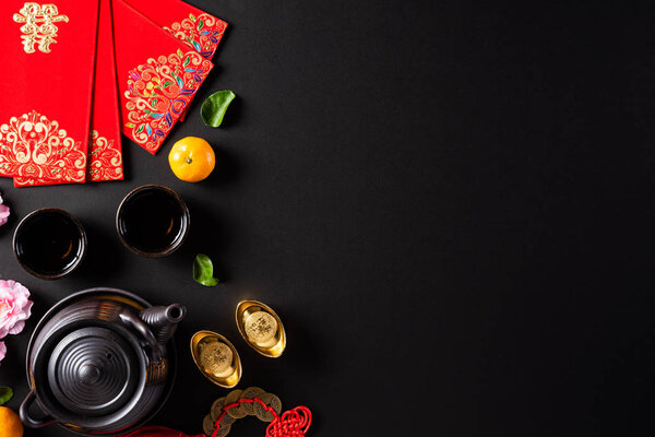 Chinese new year festival decorations pow or red packet, orange and gold ingots or golden lump on a black background. Chinese characters FU means fortune good luck, wealth, money flow.
