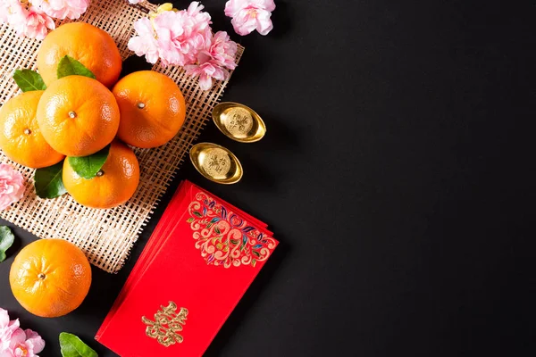Çin Yeni Yıl Festivali dekorasyonları siyah arka planda kırmızı paket, turuncu ve altın külçeler veya altın topak. Çin karakterleri Fu servet, servet, para akışı anlamına gelir.. — Stok fotoğraf