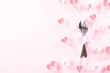 Pink paper hearts with table set with set of silverware fork and