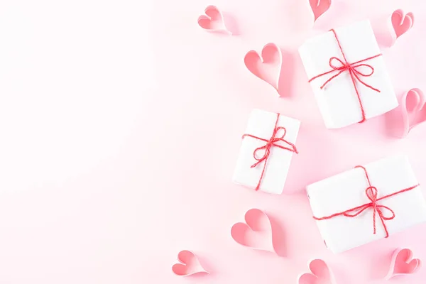 Corazones de papel rosa con caja de regalo en respaldo de papel pastel rosa claro — Foto de Stock