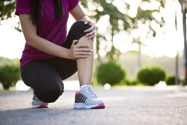 Una joven corredora de fitness siente dolor en su rodilla en el parque. Ou. — Foto de Stock