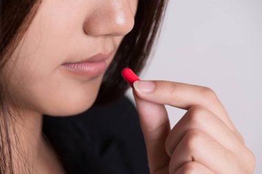 Kadının elini kırmızı haplar, ilaç hapları ve kapsülle kapat. 